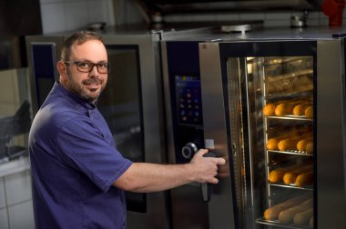 Fırının yanında fırının yanında, ekmeği fırında pişiren profesyonel fırıncı.