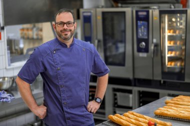 Erkek fırıncı, profesyonel fırında ekmek pişiriyor.