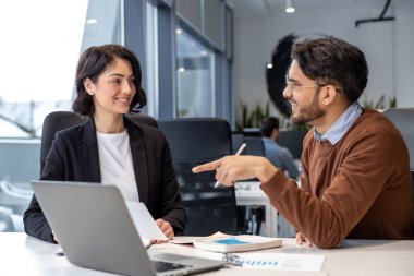 Yönetici meslektaşlar, modern ofiste oturarak yeni bir iş projesi yaratmak için dizüstü bilgisayar kullanıyorlar.