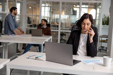 Çağdaş ofisteki çağrı merkezinde çalışan kulaklıklı genç, arkadaş canlısı bir kadın ajan.