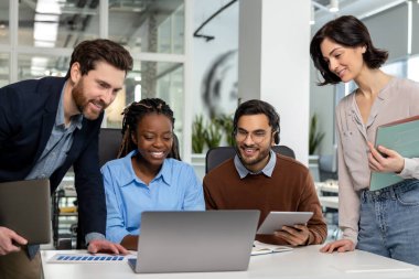 Ofiste dizüstü bilgisayarla yeni bir proje üzerinde çalışan mutlu iş adamları.
