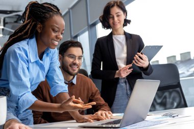 Birlikte çalışma alanında çalışırken gülümseyen bir grup mutlu iş adamı ofiste yeni bir proje üzerinde çalışıyor.