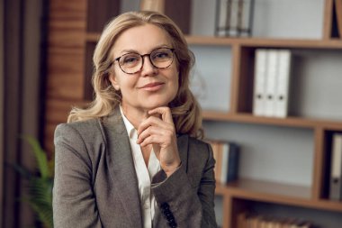 Mutlu orta yaşlı kadın psikolog kameraya bakıp gülümsüyor.