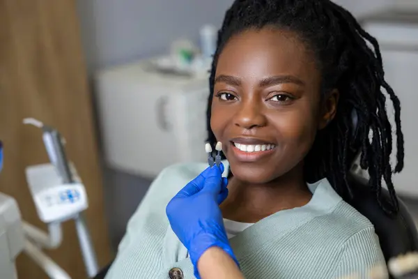 満足した女性 笑顔の暗い肌の女性 満足している見ている歯医者 ストック画像
