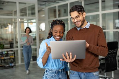 Ofisteki dizüstü bilgisayarla proje üzerinde birlikte çalışan çeşitli meslektaşlar.