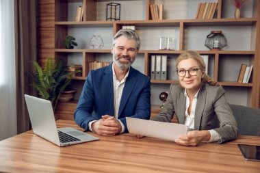 Terapi seanslarında yardımcı olan erkek ve kadın psikologlar modern ofiste işbirliği yapıyorlar.
