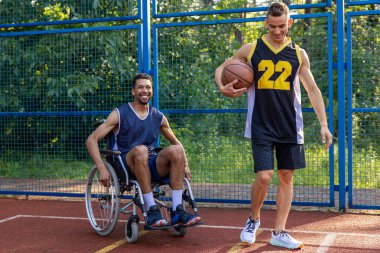 Özürlü bir sporcu ve arkadaşlarıyla basketbol sahasında egzersiz yapıyor.
