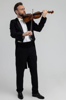 Klasik müzik performansında tutkulu bir kemancı açık gri arka planda izole edilmiş.