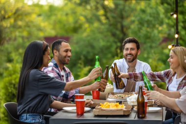 Mutlu arkadaşlar dışarıda eğleniyor bira bardakları tokuşturup keyifli bir olayı kutluyorlar.