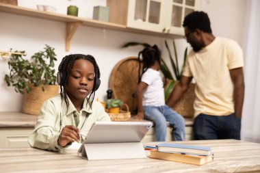 Evdeki online eğitim için tablet üzerinde dijital yazılım kullanan çok kültürlü küçük kız