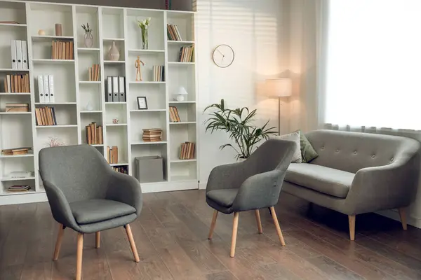 stock image Empty psychologists office with cozy chairs sofa and shelves with books