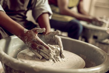 Yaradılış süreci. Islak kille çalışan ve şeklini alan ellerin resmini kapat.