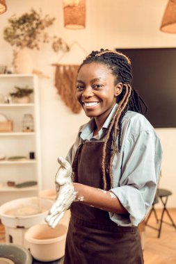 Yeni el yapımı ürün. Elinde yeni bir kilden kupayla gülümseyen genç bir kadın.