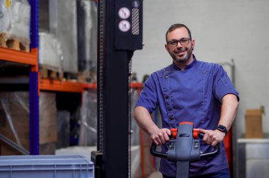 Market veya restoranın deposunda çalışan üniformalı neşeli bir adam.