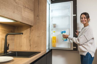 Mutfaktaki kadın. Genç siyah saçlı kadın buzdolabını açıyor ve bir şişe süt alıyor.