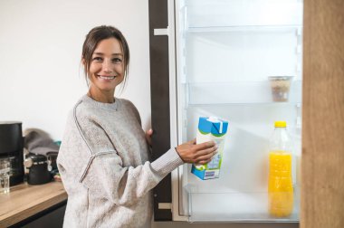 Mutfaktaki kadın. Genç siyah saçlı kadın buzdolabını açıyor ve bir şişe süt alıyor.