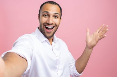 Beyaz gömlekli yakışıklı bir adam pembe arka planda izole edilmiş bir fotoğraf yapıyor.