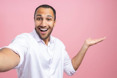 Beyaz gömlekli neşeli adam selfie yapıyor. Pembe arka planda izole edilmiş fotokopi alanını sunuyor.