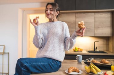 Lezzetli bir kahvaltı. Genç bir kadın mutfakta kahvaltı yapıyor ve keyifli görünüyor.