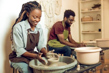 Çömlek atölyesi. İki Afro-Amerikan heykeltraş çömlek tekeri üzerinde çalışıyor.