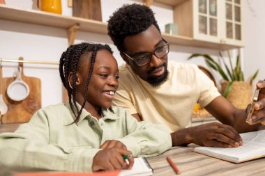 Yakışıklı baba ve tatlı küçük kızı evde ödev yaparken telefonla selfie çekiyorlar.