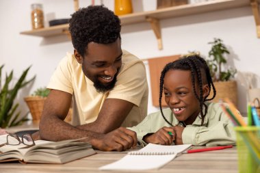 Genç, çok ırklı bir baba, kızına ev ödevinde yardım ediyor.