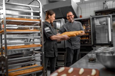 Profesyonel fırıncılar erkek ve kadın küçük pastanede taze ekmek hazırlıyorlar.