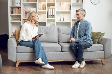 Mutsuz bir adam danışmanlık ofisinde kanepede oturup kadın psikoloğa dertlerinden yakınırken o da not alıyor.