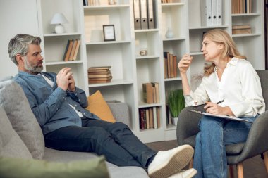 Kafkas kadın psikolog hastalarını dikkatle dinliyor. Modern rahat çalışma alanında tavsiye ve danışmanlık öneriyor..