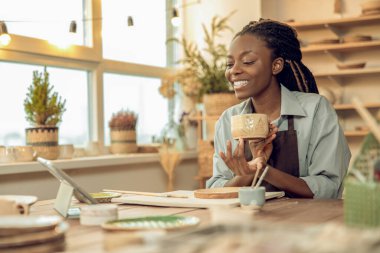 Kadın heykeltraş. Gülümseyen kadın heykeltıraş elinde yeni bir kupa tutuyor.
