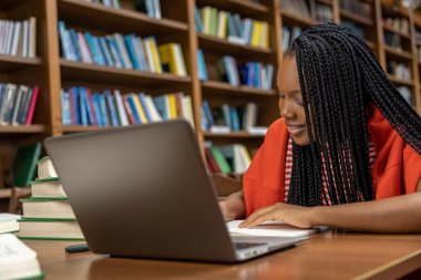 Çalışıyorum. Uzun saçlı genç bayan kütüphanede ders çalışıyor.