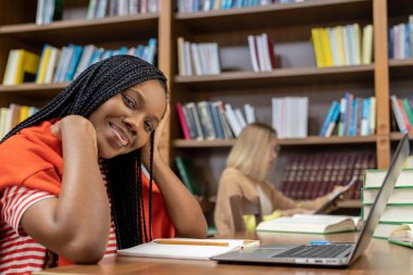 Kütüphanede. Kütüphanede dizüstü bilgisayarın başında oturan güzel genç bayan.