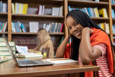 Kütüphanede. Kütüphanede dizüstü bilgisayarın başında oturan güzel genç bayan.