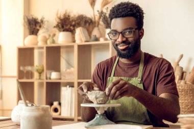 Çömlek stüdyosu. Çömlek atölyesinde kille çalışan Afrikalı Amerikalı genç bir adam.