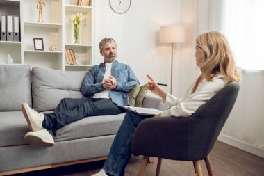 Klinikteki sarışın kadın psikologla terapi seansı sırasında orta yaşlı bir hasta.