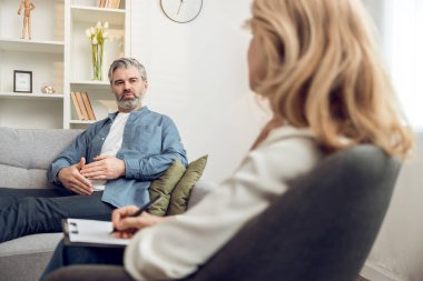 Klinikteki sarışın kadın psikologla terapi seansı sırasında orta yaşlı bir hasta.