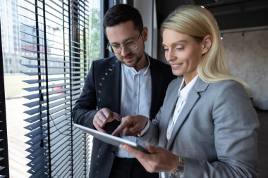 Kadın ve erkek modern ofiste iş fikirlerini dijital dizüstü bilgisayarla tartışıyor