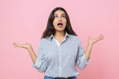 Şaşırmış Hintli kadın ellerini açıyor pembe arka planda izole edilmiş ağzı açık bir şekilde yukarı bakıyor.