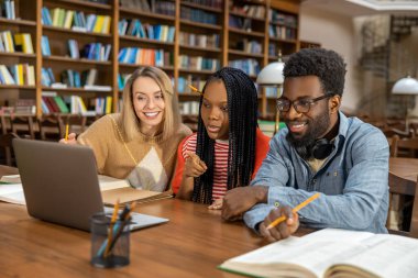 Çalışıyorum. Öğrenciler kütüphanede çalışıyor ve ilgili görünüyorlar.