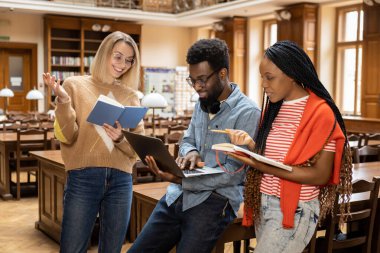 Kütüphanede. Kütüphanedeki bir grup genç meşgul ve ilgili görünüyor.