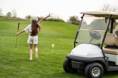 Aracın yanında golf ekipmanıyla poz veren güzel beyaz kadın.