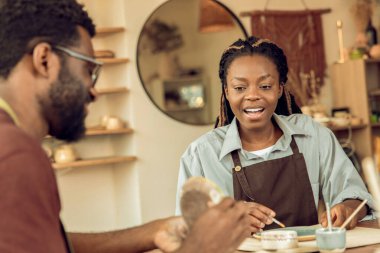 Çömlek atölyesi. Koyu tenli genç bir kadın çömlek atölyesine katılıyor.