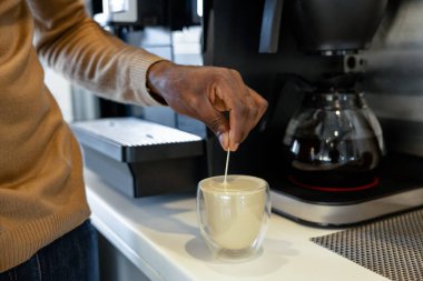 Ofis mutfağında kahve hazırlamak için mola veren tanınmamış Afrikalı Amerikalı işçi.