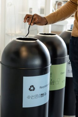 Ofisteki çöpleri ayıklayan, çöp kutusuna plastik atan tanınmamış bir adam.