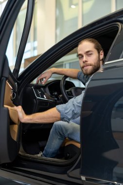 Kapıyı açıyorum. Genç sakallı adam arabada oturuyor ve arabanın kapısını açıyor.