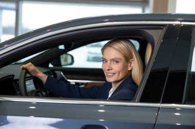 İş kadını. Kendine güvenen sarışın bir kadın arabada oturuyor ve kararlı görünüyor.