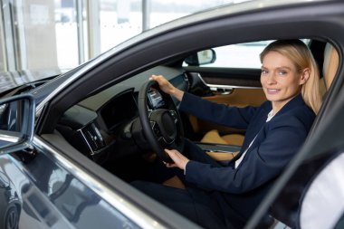 Bir araba galerisinde. Yeni arabanın yanındaki galeride zarif, güzel bir kadın.