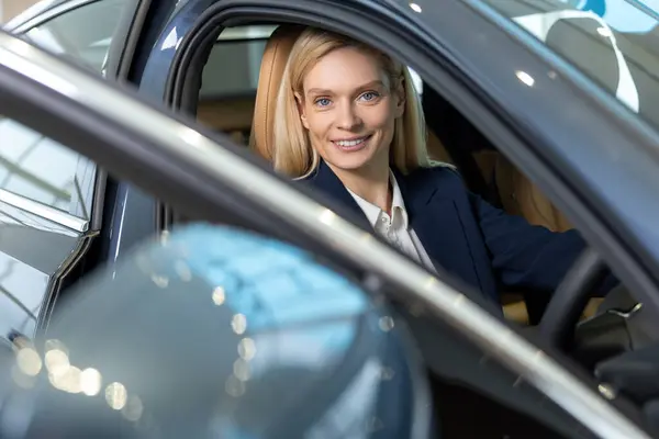 stock image In a new car. Pretty business woman sitting in a car and looking contented