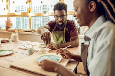 Atölye. Çömlek atölyesinde kille çalışan iki kişi.