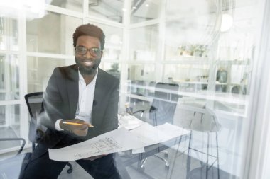 Yeni proje. Koyu tenli mimar ofisinde yeni bir proje üzerinde çalışıyor.